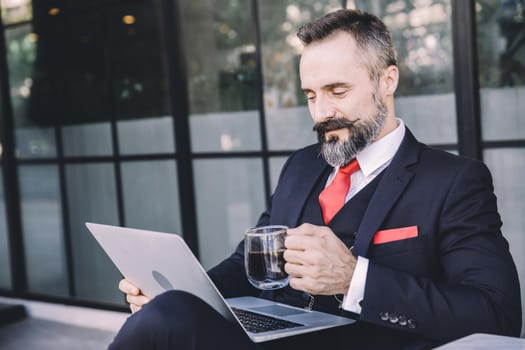 Hispanic latin businessman beard happy enjoy working with laptop computer relax at cafe drinking hot coffee