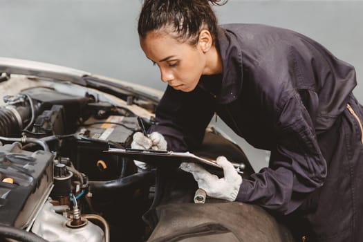 Woman garage worker maintenance checklist at automobile service center, Female in auto mechanic car technician work service check and repair customer car, inspecting car under hood