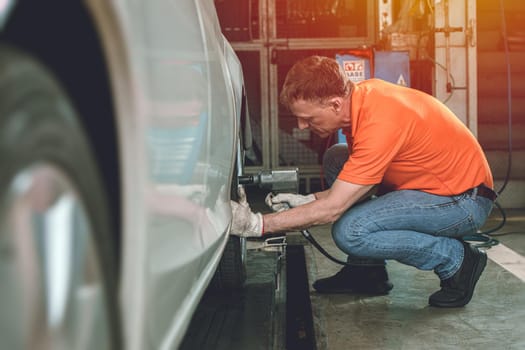 Auto mechanic worker service car by checking inflate or change tires in garage automobile workshop