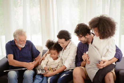Lovely home family stay together in living room father mother and grandfather playing with daughter mix race.