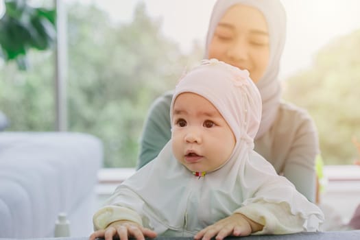 Muslim Mother look at her baby happy smiling infant home care together cute lovely childhood indoor.