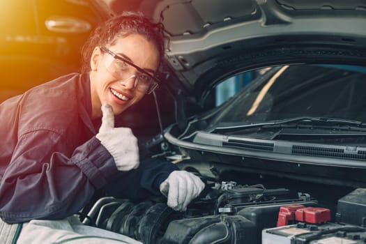 Portrait happy working woman work for auto mechanic job in garage hand thumbs up sign for good condition car engine