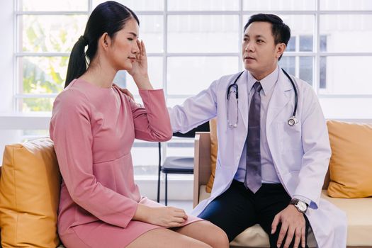 Doctor care support to help and comforting patients from stress after receiving bad medical news about illness symptom. Adult woman feel bad headache when diagnosed with cancer.