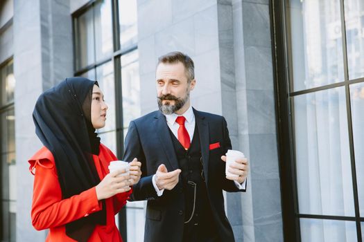 Arab Muslim business people man and woman morning coffee walking talking together