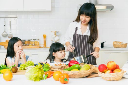 Family cooking in the kitchen with children happy enjoy eating healthy food fruits and vegetable, candid moment together.