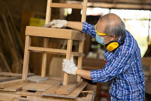 Elder worker wood woodcraft retire hobby for good retirement, Asian male mature professional master of making wooden furniture with face mask protective.