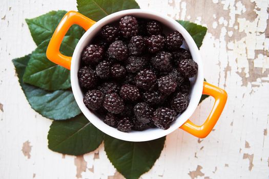 A full blackberry plate is on an old wooden background.