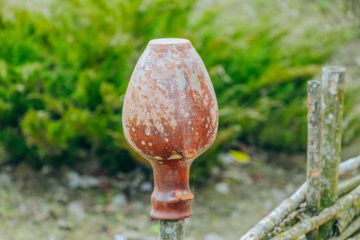 Antique clay jug hanging on a wicker fence . High quality photo