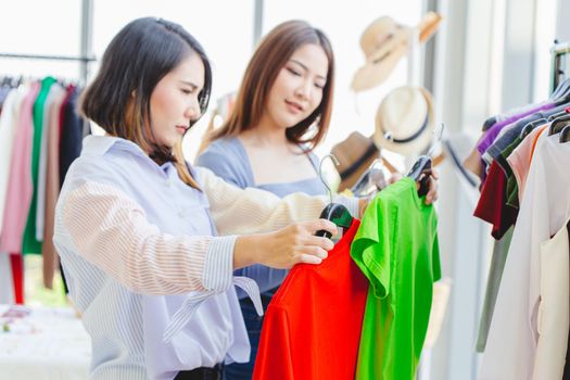 Women customer choosing clothes looking for new shirt in fashion shop with friend happy smile.