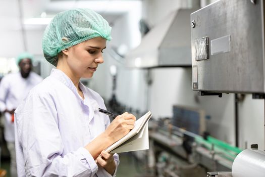 Quality control and food safety caucasian women worker staff inspection the product standard in the food and drink factory production line.