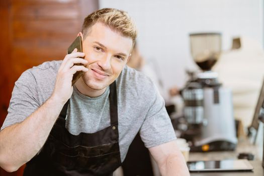 Barista male calling talk with customer to receive cafe beverage order by phone happy smile.