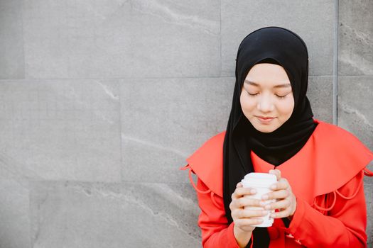 Arab Muslim women drinking coffee in the morning outdoor, Asian businesswoman young girl smiling hand hold coffee cup standing closeup.