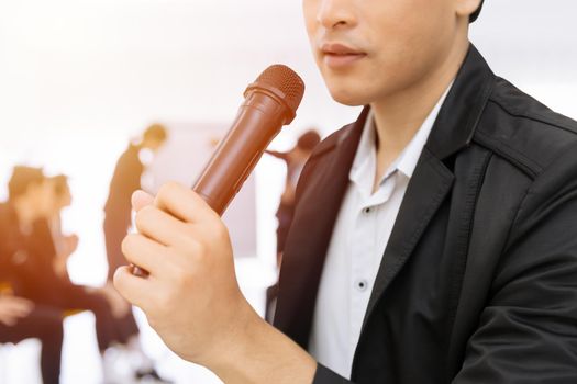 Closeup Male hand holding Microphone speaking in business seminar. Speaker man lecture meeting or talk show concept.