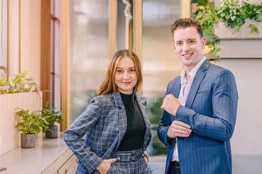 Portrait caucasian business man and women standing together in modern office with British suit fashion clothes style happy smiling.