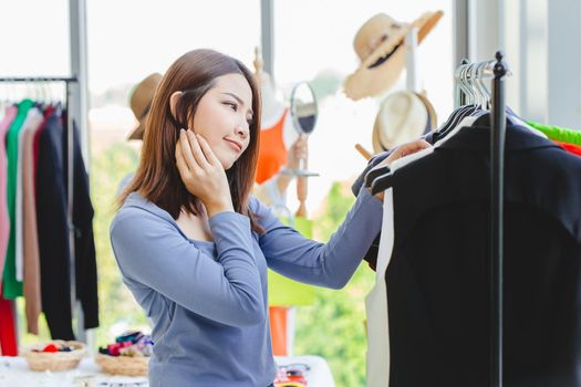 Women customer thinking and hesitate to choosing clothes black color looking for new shirt in fashion shop.