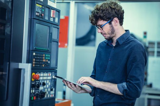 Young Engineer American professional staff worker operate advance machine with tablet computer.