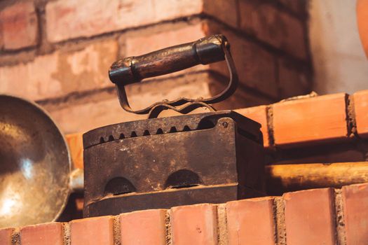 Vintage cast iron charcoal iron standing on brick wall . High quality photo