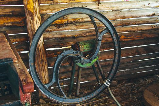 Steel old rusty wheel from agricultural machinery near wooden wall. High quality photo