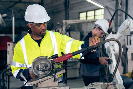 Factory workers working with adept robotic arm in a workshop . Industry robot programming software for automated manufacturing technology .