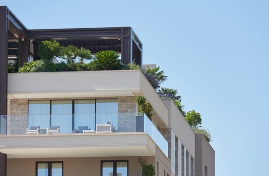 Palms and plants grow on the rooftop patio on modern residential building in europe.