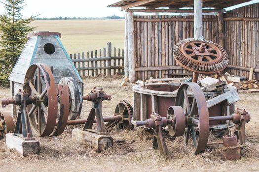 Rusty remains of old agricultural machinery on the street near the fence. High quality photo