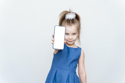 I Recommend. Little girl in blue dress showing blank cell phone screen grey studio wall