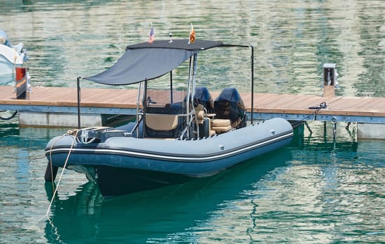 Powerful small boat of gray color with two engines at the pier.