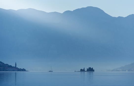 Small island against the backdrop of large mountains, Morning landscape in the adriatic sea in Montenegro.