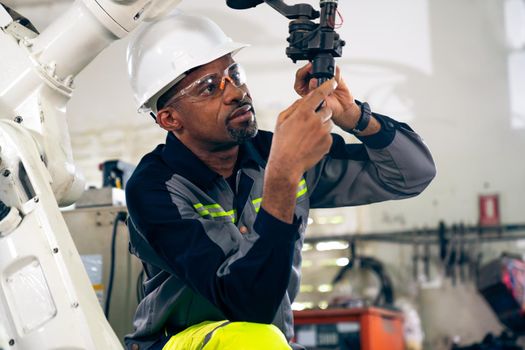African American factory worker working with adept robotic arm in a workshop . Industry robot programming software for automated manufacturing technology .