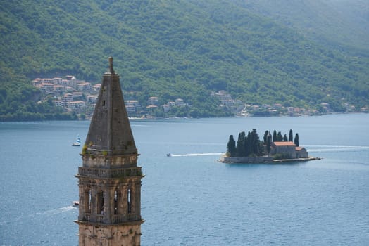 Tower of the old church on the background of the sea and the island in Montenegro, Perast.