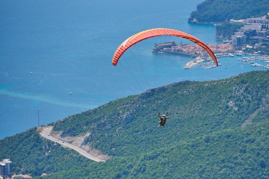 Two person fly on paragliding against city of Budva.
