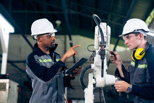 Factory workers working with adept robotic arm in a workshop . Industry robot programming software for automated manufacturing technology .