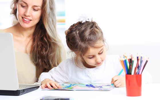 Young mother with little daughter sitting together at home