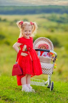 girl with a toy stroller walks in nature