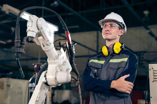 Young factory worker working with adept robotic arm in a workshop . Industry robot programming software for automated manufacturing technology .