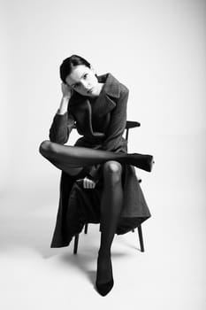 beautiful woman in a coat sits on a chair. High quality photo