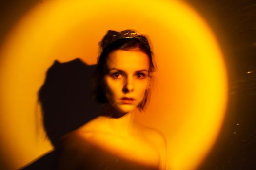 woman with a crown on her head in yellow light, art portrait. High quality photo