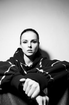 beautiful brunette girl in a black hoodie, light background. High quality photo