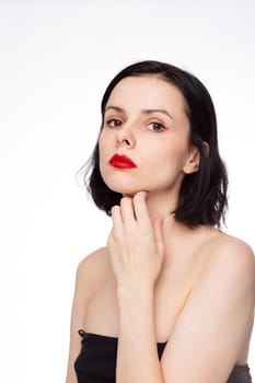 brunette woman with red lips in black top, white studio background. High quality photo