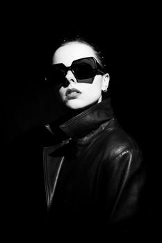 woman in leather coat and sunglasses, black background. High quality photo