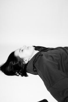 a woman in a black hoodie lies on the floor, black and white photography. High quality photo