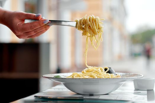 delicious pasta on a fork in a summer cafe with a picturesque background. High quality photo