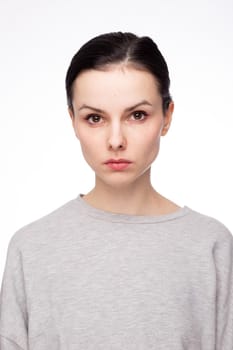 cute brunette woman with gray sweatshirt, white background. High quality photo