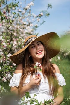 Spring concept. Nature. Portrait of young caucasian woman enjoying the flowering of an apple trees, walking in spring apple gardens