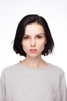cute brunette woman with gray sweatshirt, white background. High quality photo