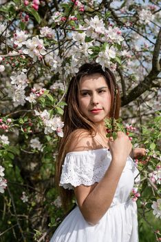 Spring concept. Nature.Young caucasian woman enjoying the flowering of an apple trees, walking in spring apple gardens