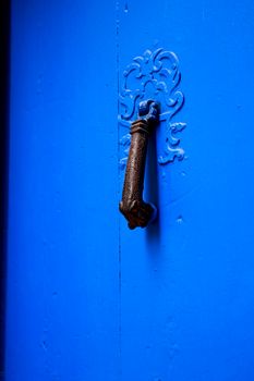 Blue wooden door with black metal knocker in Villajoyosa, Alicante, Spain.