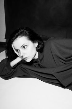 a woman in a black hoodie lies on the floor, black and white photography. High quality photo