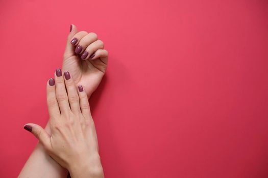 Stylish trendy female manicure. Beautiful young woman's hands on red background.