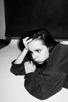a woman in a black hoodie lies on the floor, black and white photography. High quality photo